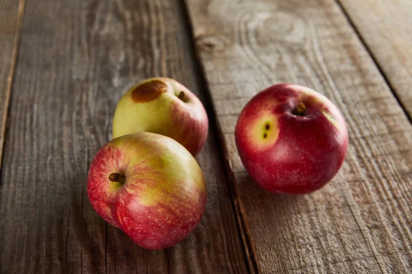 Apples with rotten spot on wooden surface — Stock Photo