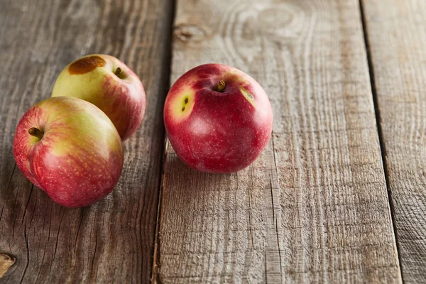 Apples with small rotten spot on wooden surface — Stock Photo