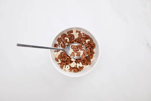 Vista superior da tigela com chocolate e cereal branco com leite e colher na superfície de mármore — Fotografia de Stock