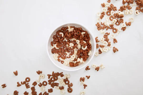 Top view of bowl with chocolate and white cereal on marble surface — Stock Photo