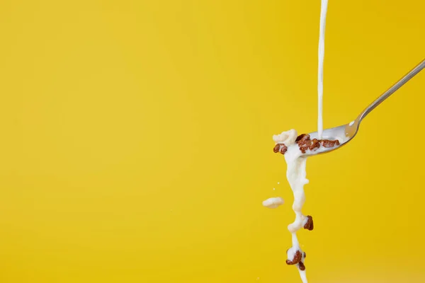 Spoon with assorted cereal and milk splashes isolated on yellow — Stock Photo