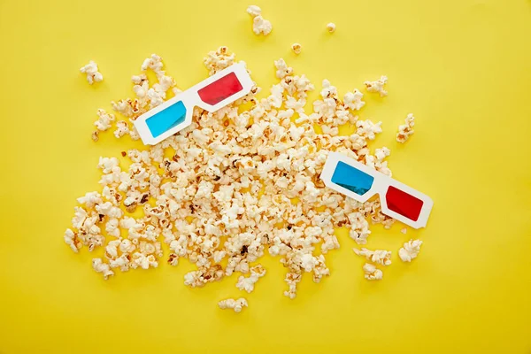 Top view of delicious popcorn scattered near 3d glasses on yellow background — Stock Photo