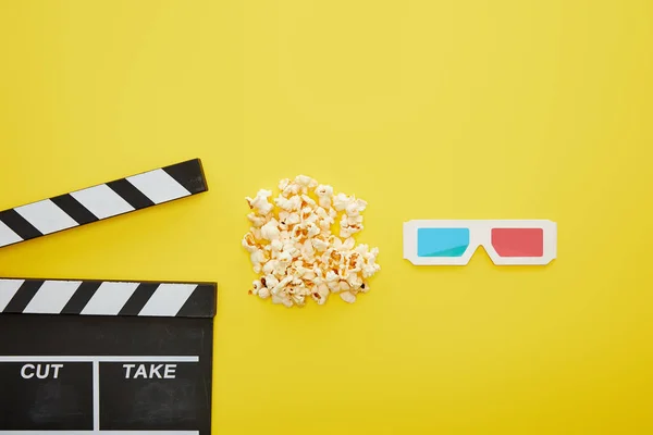 Вид сверху на вкусный попкорн рядом с 3D очки и доска хлопок на желтом фоне — стоковое фото