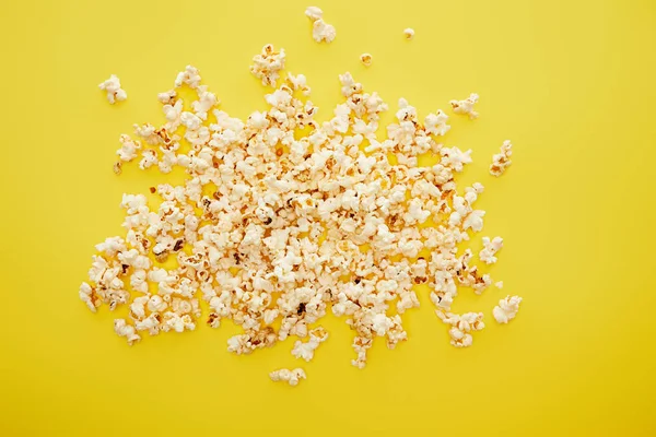 Top view of tasty popcorn scattered on yellow background — Stock Photo