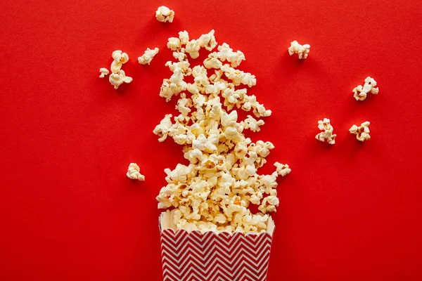 Top view of delicious popcorn scattered on red background — Stock Photo