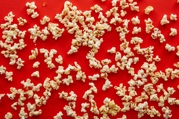 Top view of fresh popcorn scattered on red background — Stock Photo