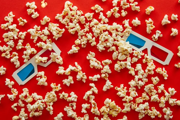 Вид сверху на 3d очки на вкусный разбросанный попкорн на красном фоне — Stock Photo