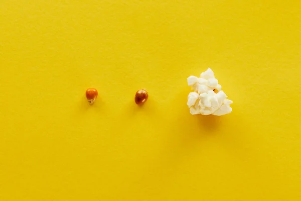 Top view of delicious popcorn and corn on yellow background — Stock Photo