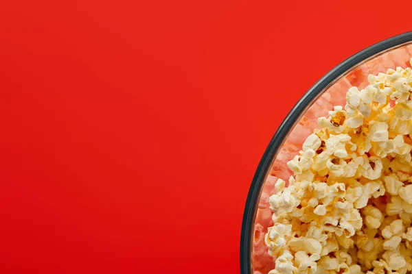 Top view of delicious popcorn in glass bowl isolated on red — Stock Photo