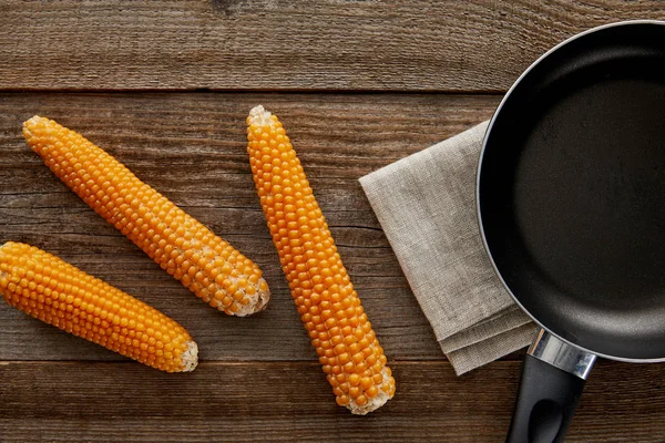 Top view of delicious corn near frying pan on wooden background — Stock Photo