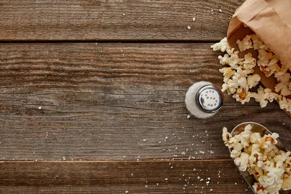 Blick von oben auf leckeres Popcorn mit Salz auf Holzgrund — Stockfoto