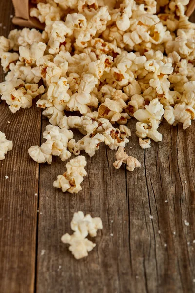 Delicious popcorn scattered on wooden background — Stock Photo