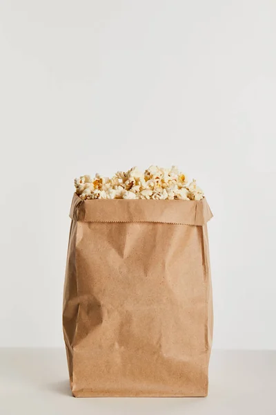 Смачний попкорн в паперовій сумці ізольований на сірому — стокове фото