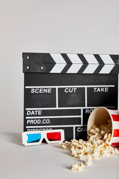 Delicious popcorn with clapper board and 3d glasses isolated on grey — Stock Photo