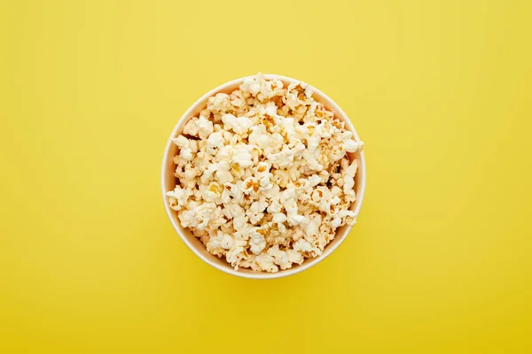 Top view of delicious fresh popcorn in bucket on yellow background — Stock Photo