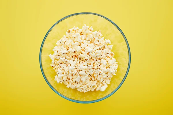 Top view of delicious fresh popcorn in glass bowl on yellow background — Stock Photo