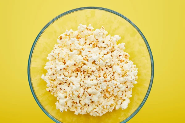 Top view of delicious popcorn in glass bowl on yellow background — Stock Photo