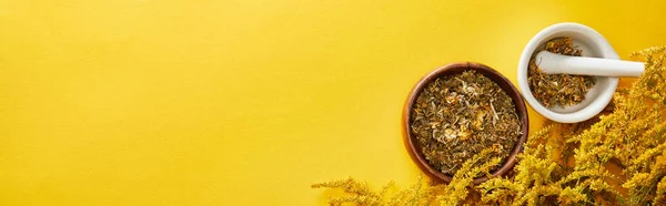 Panoramic shot of mortars with pestle on yellow background with goldenrod — Stock Photo