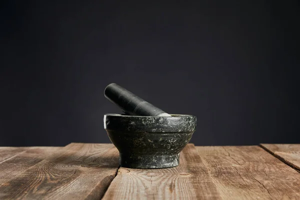 Grey stone mortar on wooden table isolated on black — Stock Photo