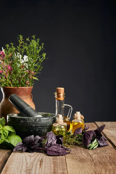 Malta grigia vicino vaso di argilla con erbe su tavolo di legno isolato su nero — Foto stock