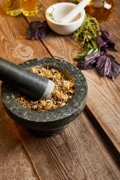 Mortars with pestles with herbal mix near fresh basil on wooden surface — Stock Photo