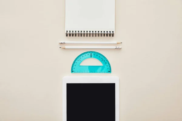 Vista superior de lápices, cuaderno y regla cerca de tableta digital con pantalla en blanco aislada en beige - foto de stock