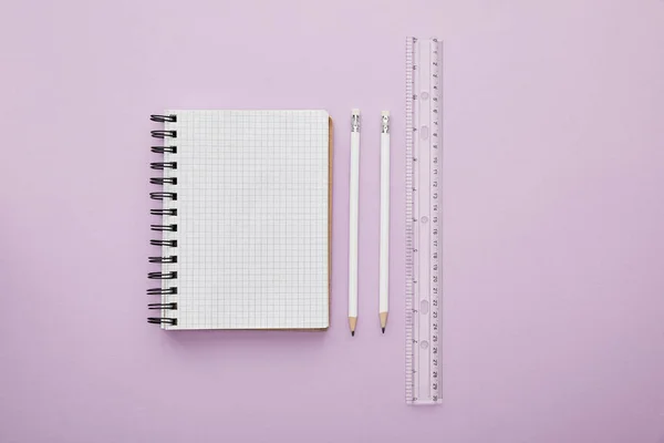 Vista superior del cuaderno cerca de lápices y regla aislada en púrpura - foto de stock