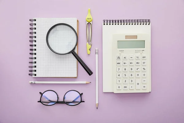 Vista superior da lupa no notebook perto de calculadora e óculos isolados em roxo — Fotografia de Stock