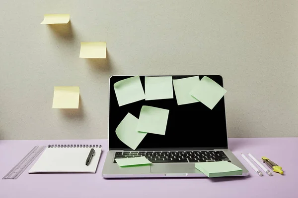 Notas verdes pegajosas no laptop perto de artigos de papelaria em cinza e roxo — Fotografia de Stock
