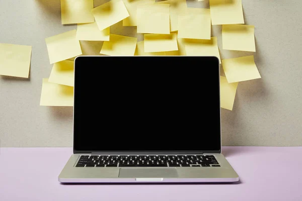 Ноутбук з порожнім екраном біля жовтих липких нот на сірому і фіолетовому — стокове фото