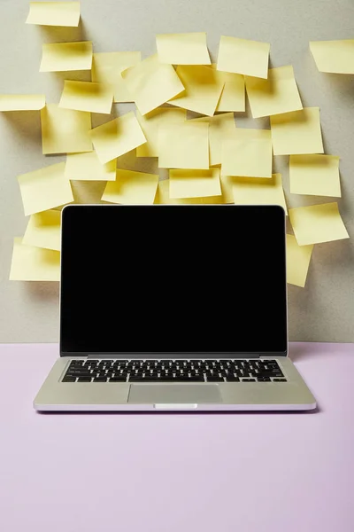 Laptop with blank screen near empty sticky notes on grey and purple — Stock Photo