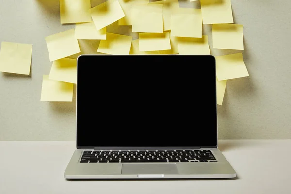 Laptop with blank screen near empty sticky notes on grey and white — Stock Photo