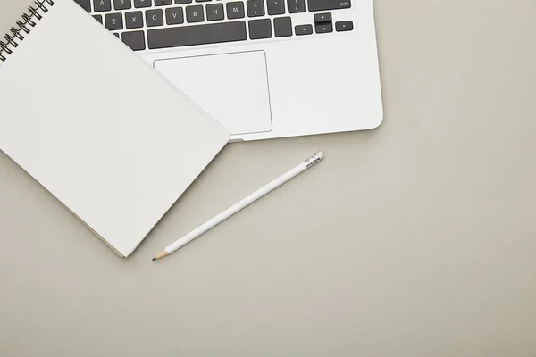 Top view of laptop with notebook and pen isolated on grey — Stock Photo