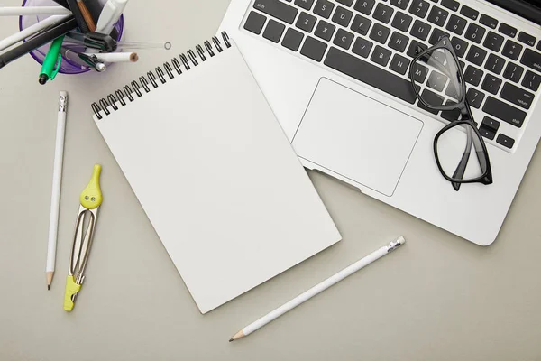 Top view of notebook near stationery and laptop isolated on grey — Stock Photo