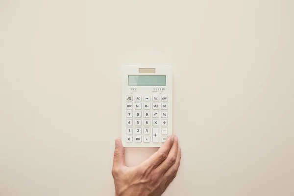 Vista recortada de hombre sosteniendo calculadora aislado en beige - foto de stock
