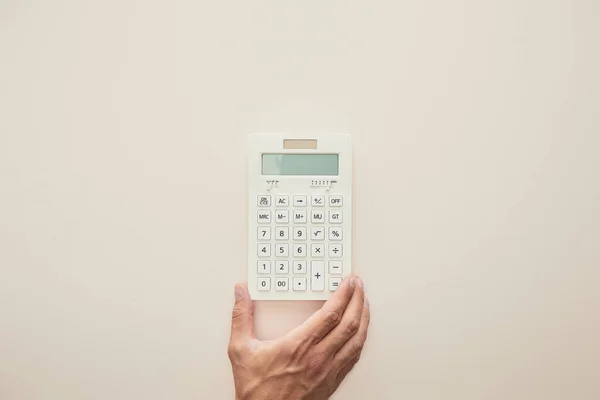 Cropped view of man holding calculator isolated on beige — Stock Photo