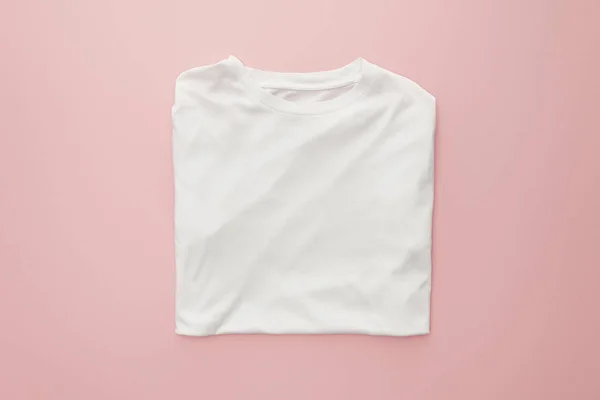 Vista superior de branco branco dobrado t-shirt sobre fundo rosa — Fotografia de Stock