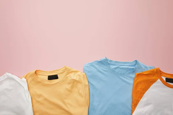 Vista superior de camisetas coloridas dobradas no fundo rosa — Fotografia de Stock