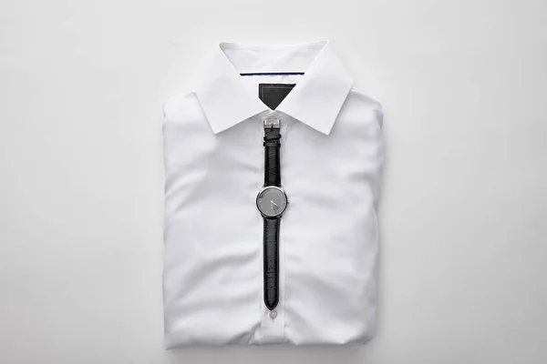 Top view of watches on plain folded shirt on white background — Stock Photo