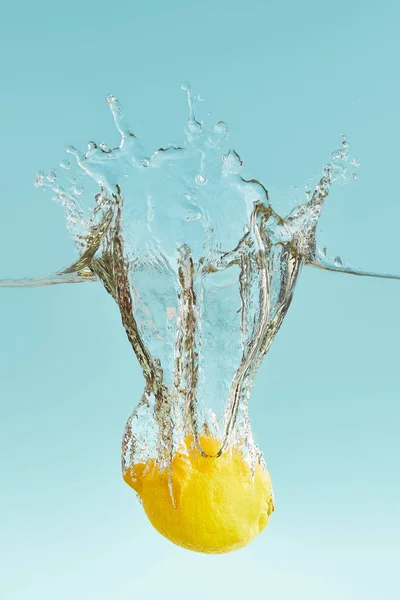 Limone maturo che cade in profondità in acqua con spruzzi su fondo blu — Foto stock