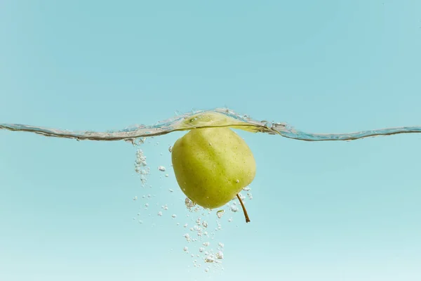 Ripe green apple in water with bubbles on blue background — Stock Photo