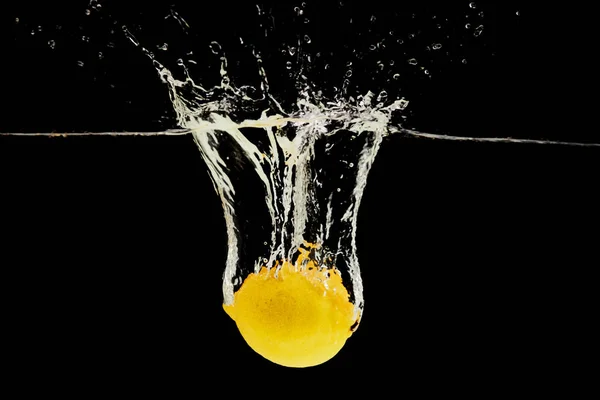 Ripe lemon falling deep in water with splash isolated on black — Stock Photo