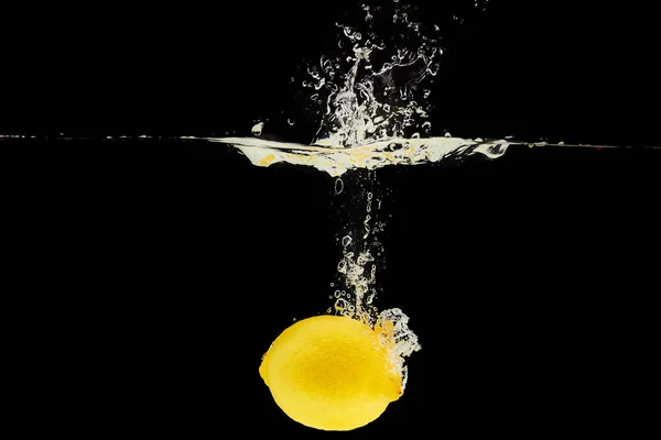 Yellow ripe lemon falling deep in water with splash isolated on black — Stock Photo