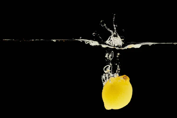 Gelbe Zitrone fällt tief ins Wasser mit Spritzer isoliert auf schwarz — Stockfoto