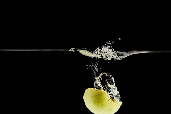 Green apple half falling deep in water with splash isolated on black — Stock Photo