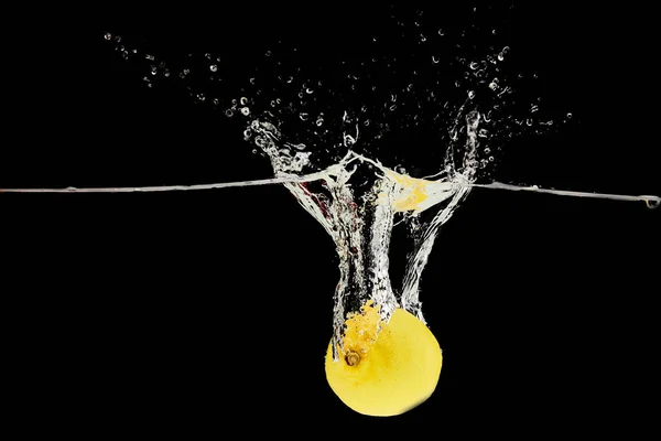 Frische Zitrone fällt tief ins Wasser mit Spritzer isoliert auf schwarz — Stockfoto