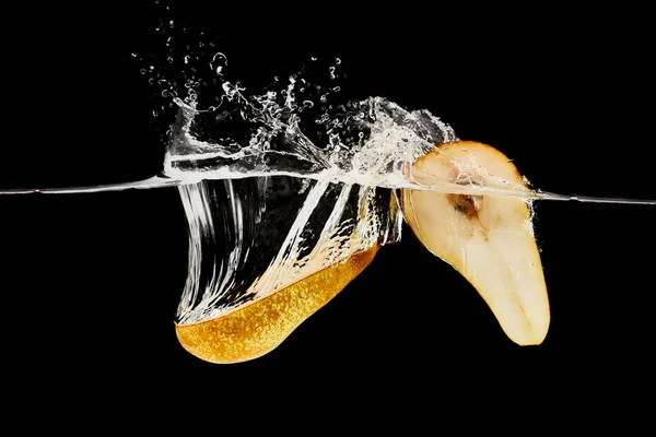Metà pera che cade in acqua con spruzzi isolati su nero — Foto stock