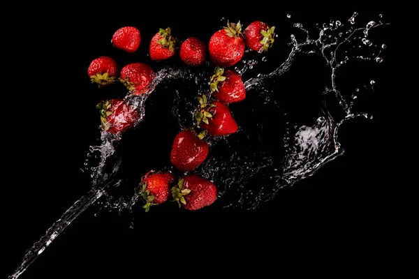 Draufsicht auf reife Erdbeeren mit Wasserspritzer isoliert auf schwarz — Stockfoto