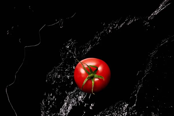 Top view of ripe red tomato in clear water puddle isolated on black — Stock Photo