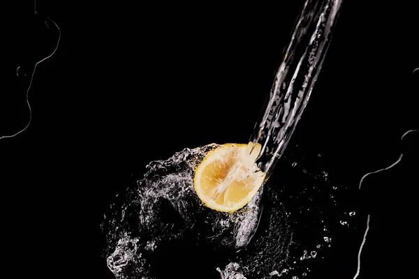 Vue de dessus de la moitié de citron avec éclaboussure d'eau claire isolé sur noir — Photo de stock